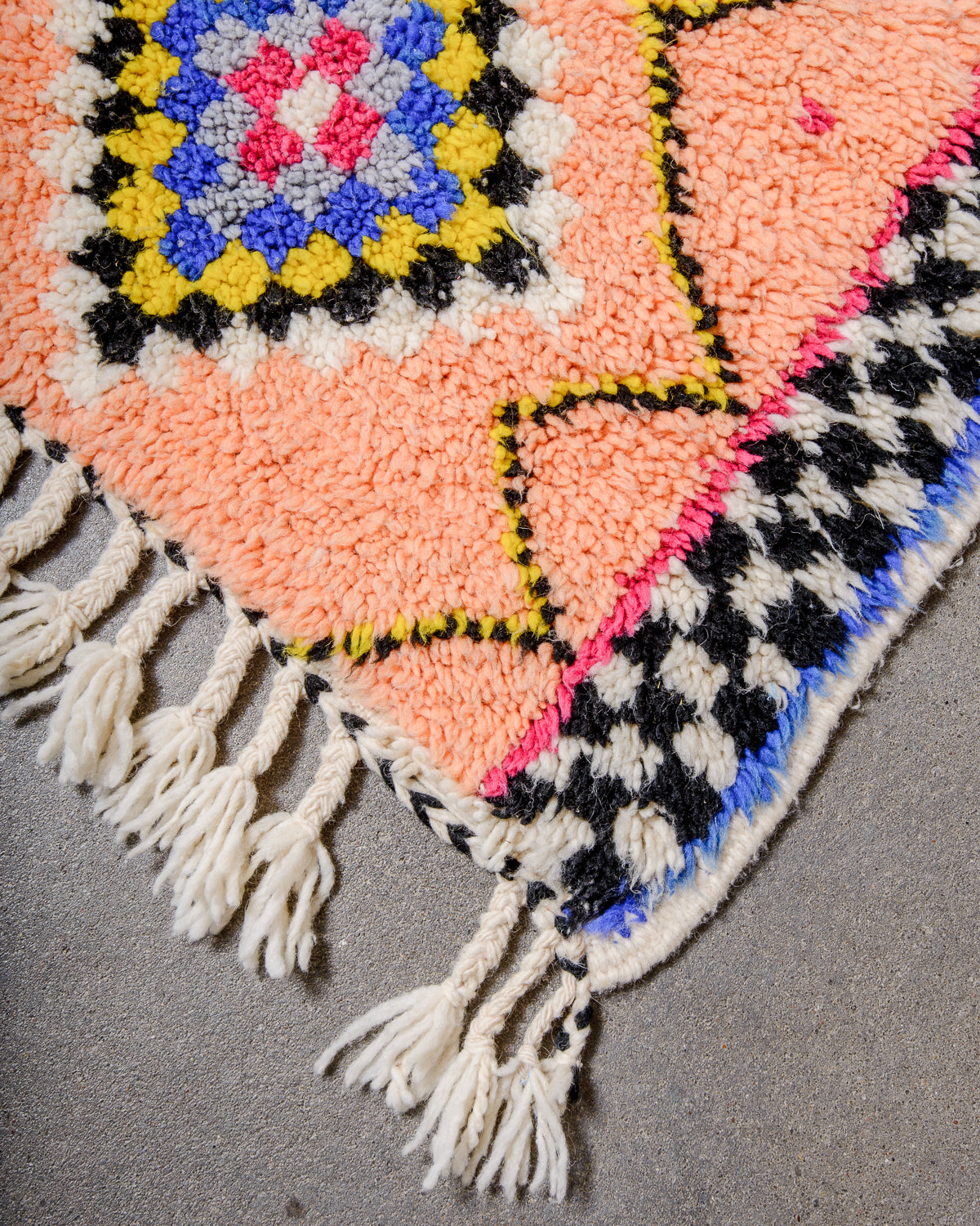 Corner of Berber runner rug with fluffy wool pile, tightly woven end and natural wool tassels.